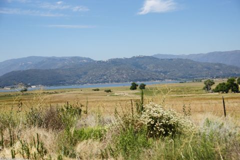 1995 Ford Taurus - A wide view of a natural landscape a lake, rolling hills, and mountains under a clear sky.