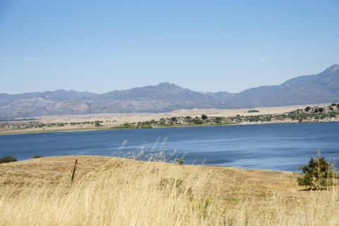 1995 Ford Taurus - A wide shot of a lake with mountains in the distance, framed by dry grass.