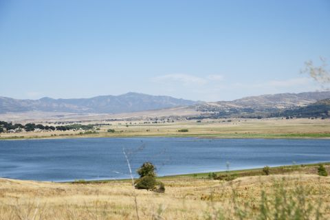 1995 Ford Taurus - A wide view of a lake and arid hills under a bright blue sky, with dry grass in the foreground.