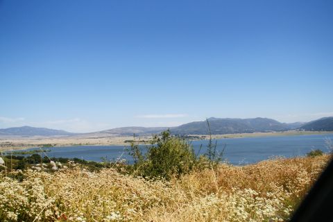 1995 Ford Taurus - A wide shot captures a tranquil lake surrounded by hills under a clear blue sky.