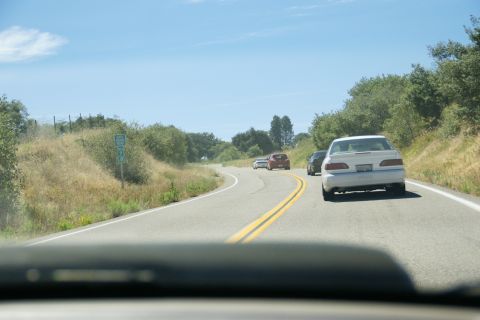 1995 Ford Taurus - A 1995 Ford Taurus is seen from behind while driving on a winding road with other vehicles.