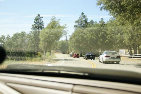 1995 Ford Taurus - Multiple vehicles travel along a rural road on a sunny day.