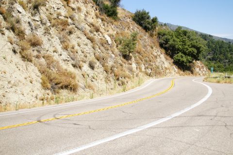 1995 Ford Taurus - A paved road curves through a dry, mountainous landscape under a clear blue sky.