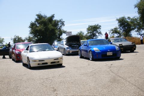 1995 Ford Taurus - A collection of vehicles gathered outdoors on a sunny day, with several cars lined up.