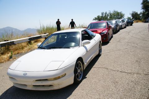 1995 Ford Taurus - A white Ford Probe is parked on the side of a road with other vehicles in the background.