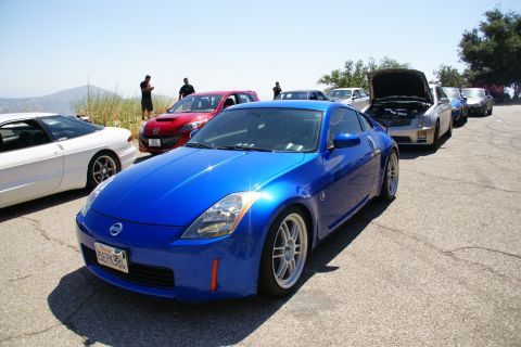 1995 Ford Taurus - A line of cars parked on a hill, led by a bright blue Nissan 350Z.