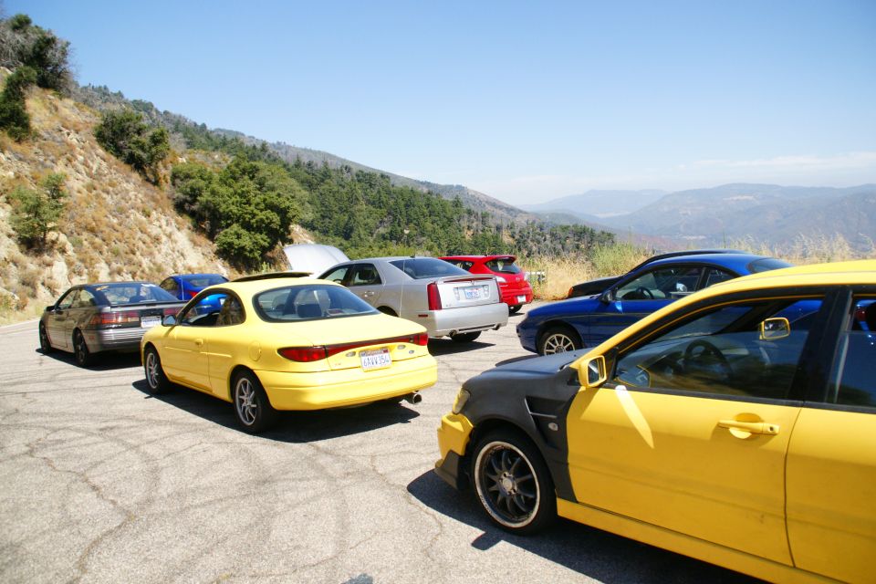 Yellow coupe with a sunroof and a California license plate parked on a mountain road