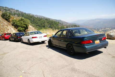 1995 Ford Taurus - A dark green 1995 Ford Taurus is parked on a scenic mountain overlook, with other vehicles in the background.