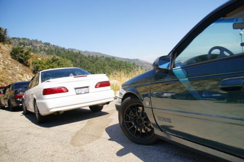 1995 Ford Taurus - A white 1995 Ford Taurus is parked on a road with a mountainous backdrop.