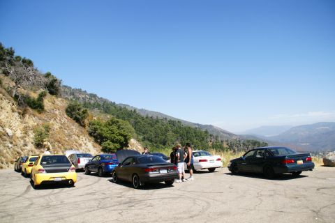 1995 Ford Taurus - A gathering of cars on a scenic overlook with a mountainous landscape in the background.
