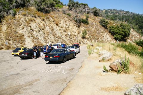 1995 Ford Taurus - A group of vehicles are parked on the side of a road with a hill in the background.