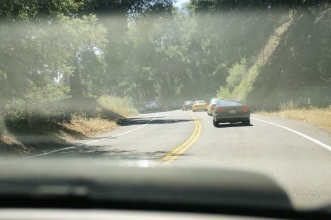1995 Ford Taurus - A line of cars travels down a dusty road, kicking up a cloud of dust behind them.