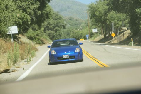 1995 Ford Taurus - A blue sports car is seen driving on a winding road through a wooded, hilly area.