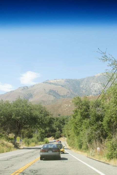 1995 Ford Taurus - Cars travel along a scenic route with mountains and trees visible in the background.