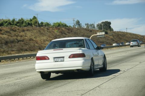 1995 Ford Taurus - A white 1995 Ford Taurus sedan drives on a sunny highway.