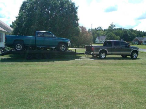 1997 Dodge 2500 - A green Dodge Ram pickup is loaded onto a trailer, towed by a gray Ford F-250 Super Duty pickup.
