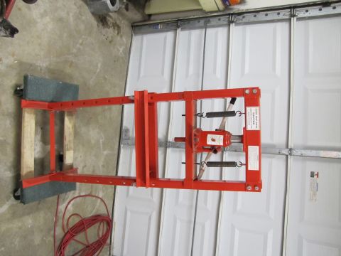 1995 Ford Bronco - A red metal frame with springs and a jack is shown on a concrete floor in front of a white garage door.