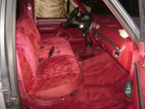 1995 Ford Bronco - The interior of a vehicle with red velour seats and carpeting is visible.