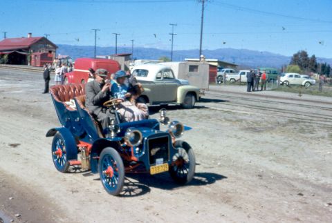 1969 MINI Cooper - An early 20th-century automobile, painted blue with red accents, carries four passengers on a dirt road.