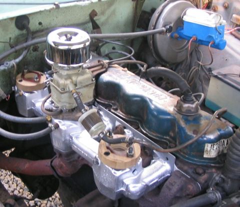 1981 Ford Bronco - Overhead view of an inline six-cylinder engine in an engine bay, fitted with a polished aluminum intake manifold, a single carburetor under…