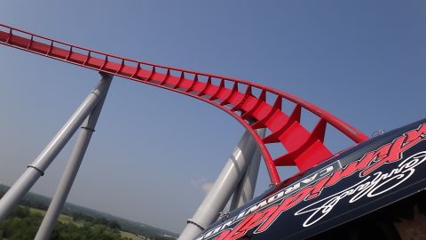 1992 Ford Taurus - A roller coaster track curves sharply against a clear blue sky, with a portion of a vehicle visible in the foreground.