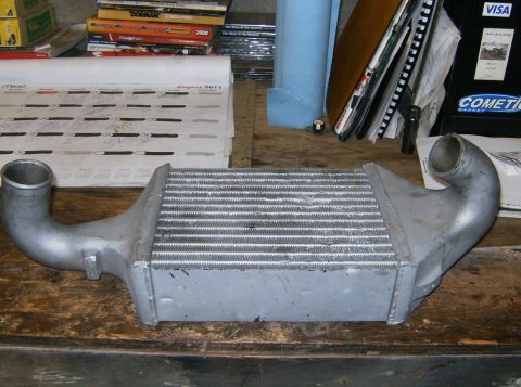 2000 Ford E350 - An intercooler part is shown on a wooden surface, with various manuals and a calendar in the background.