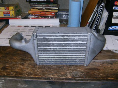 2000 Ford E350 - Intercooler part shown on a workbench with various manuals and supplies in the background.