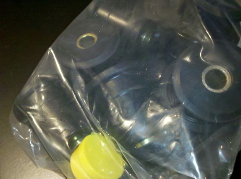 1998 Ford Crown Victoria - sealed clear bag holds several black rubber or polyurethane bushings with metal sleeves, plus a bright yellow piece.