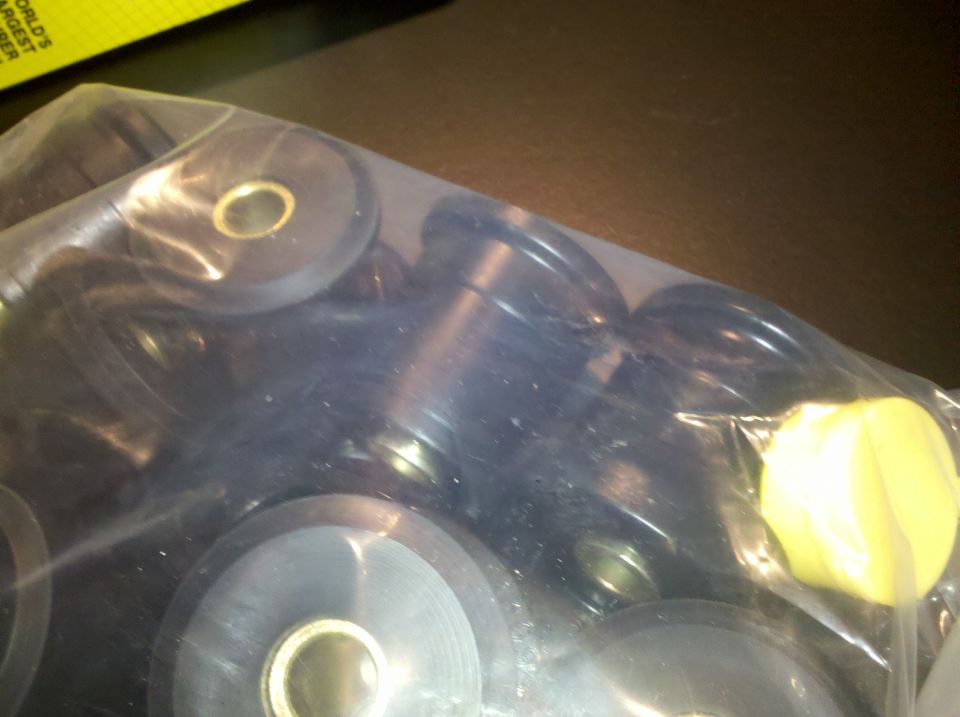 Clear bag of black bushings and yellow polyurethane bushings beside a yellow label