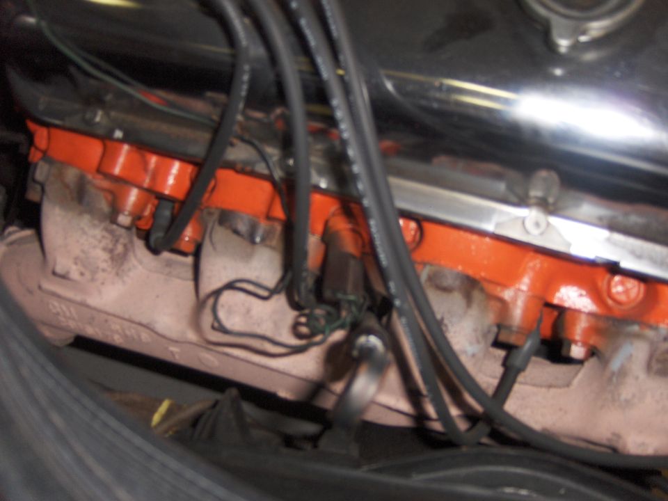 Orange-painted V8 cylinder head, exhaust manifold and plug wires in an engine bay