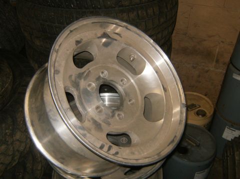 2000 Ford E350 - A single aluminum wheel is shown, dusty and resting on a stack of tires.