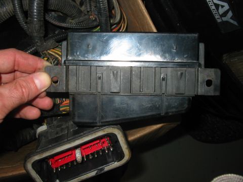 1992 Ford Bronco - Close-up of a wiring harness connector and its mounting bracket, with a hand holding the bracket.