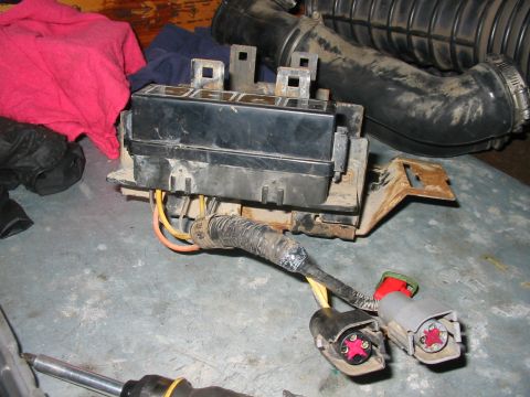 1992 Ford Bronco - A close-up view of a vehicle's fuse box and associated wiring, with an air intake tube visible in the background.