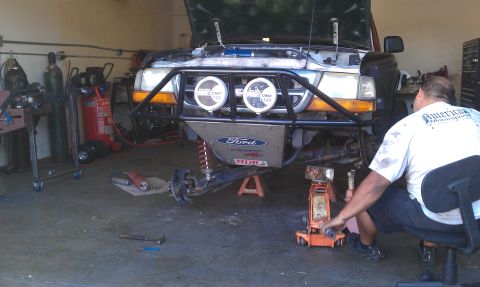 1992 Ford Ranger - A mechanic works on the front end of a 1992 Ford Ranger truck that is raised on jacks in a garage.
