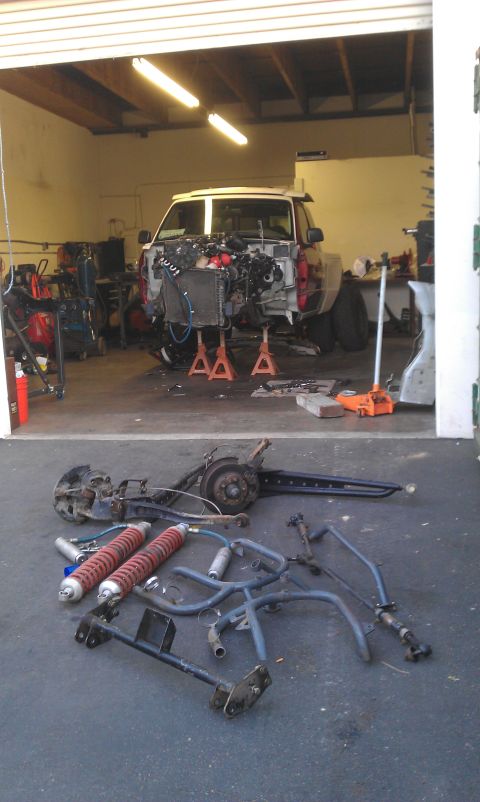 1992 Ford Ranger - A truck is disassembled in a garage, with its engine removed and various suspension components laid out on the floor.