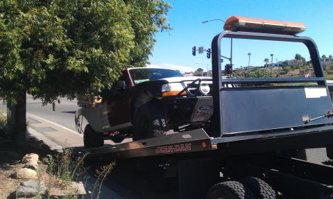 1992 Ford Ranger - A 1992 Ford Ranger is loaded onto a tow truck, showing its front-right side.
