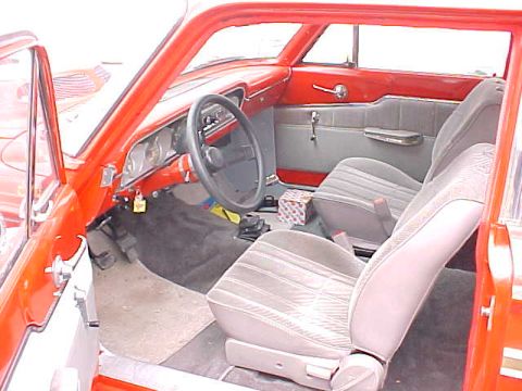 1969 Ford Torino - The interior of a vintage red car features light-colored seats and a black steering wheel.