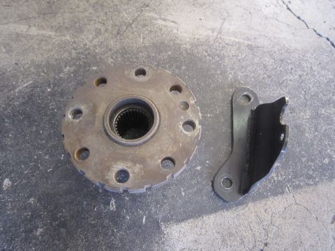 1996 Ford Bronco - A metal flange and bracket, likely automotive parts, are shown on a concrete floor.