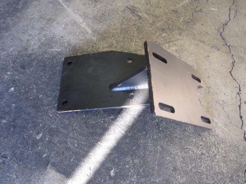 1996 Ford Bronco - A metal bracket, likely a vehicle part, is shown resting on a concrete surface.