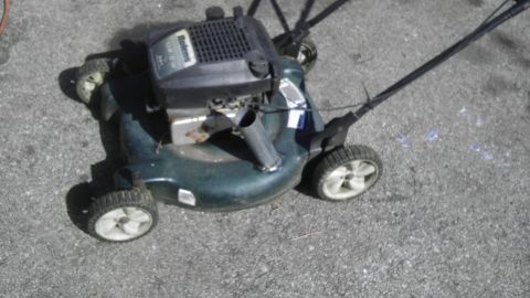 1989 Ford Bronco - A green lawn mower sits on a paved surface, its engine and wheels clearly visible.