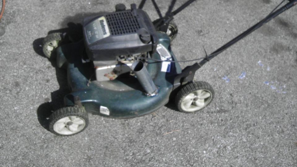 Green lawn mower with a black engine and wheels, viewed from a high angle