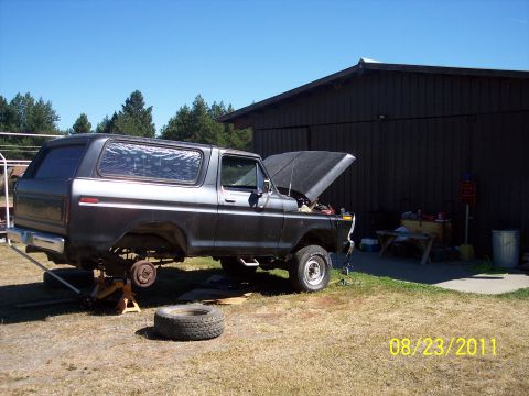 1978 Ford Bronco - 1978 Ford Bronco undergoing repairs in a yard next to a dark barn.