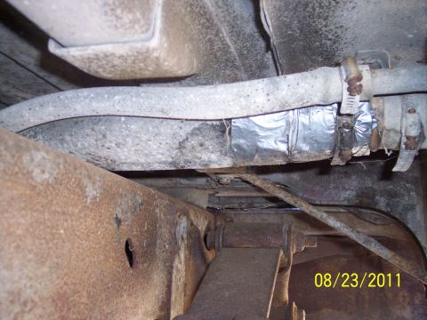 1978 Ford Bronco - A close-up view of the undercarriage shows a fuel line that has been repaired with foil tape and hose clamps.