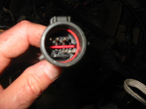 1992 Ford Bronco - A hand holds a wiring harness connector, revealing its internal pins and wiring.