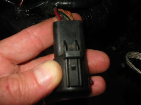 1992 Ford Bronco - A hand holds a black wiring harness connector with visible red and orange wires.