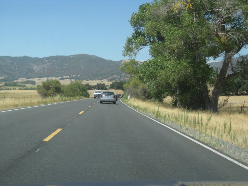 Silver sedan and white SUV drive on a rural highway