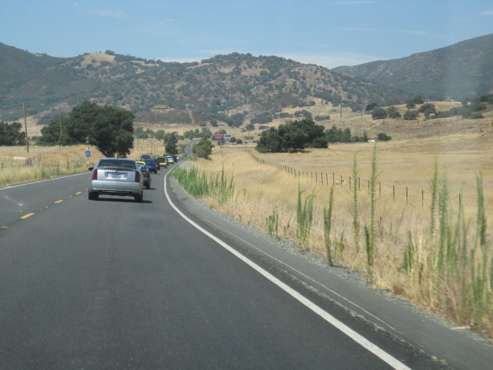 Silver sedan driving on a highway with other cars in a line