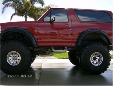 2007 Ford F-250 - This red SUV, likely a 1996 model, is modified with large off-road tires and fender flares.