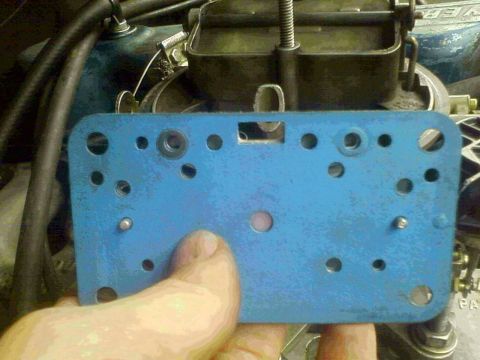 1981 Ford Bronco - A blue carburetor spacer plate is shown in front of engine parts, with a 'SUPERMOTORS' watermark at the bottom.