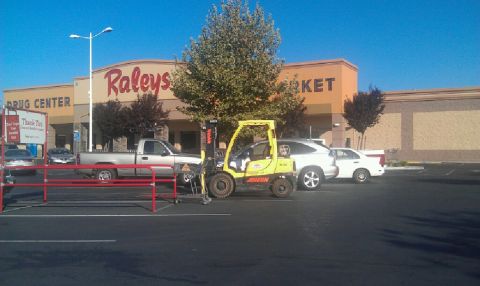 1989 Ford Bronco - Forklift parked in a grocery store parking lot next to a pickup truck and cars.